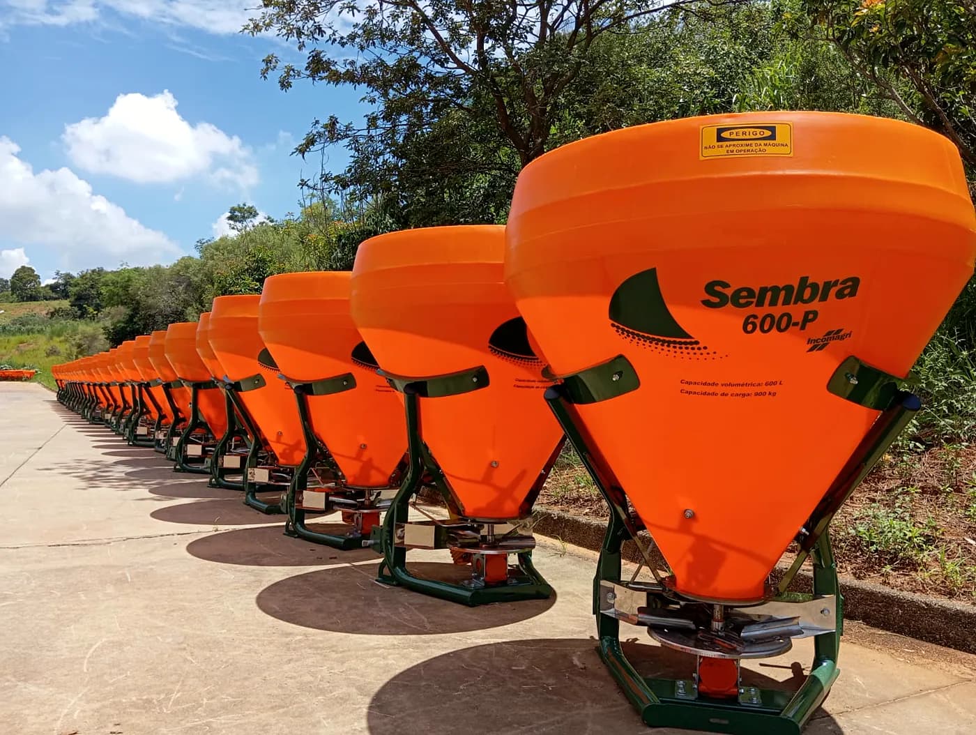 Fila de distribuidores Sembra laranja da Incomagri enfileirados no pátio, sob céu aberto.