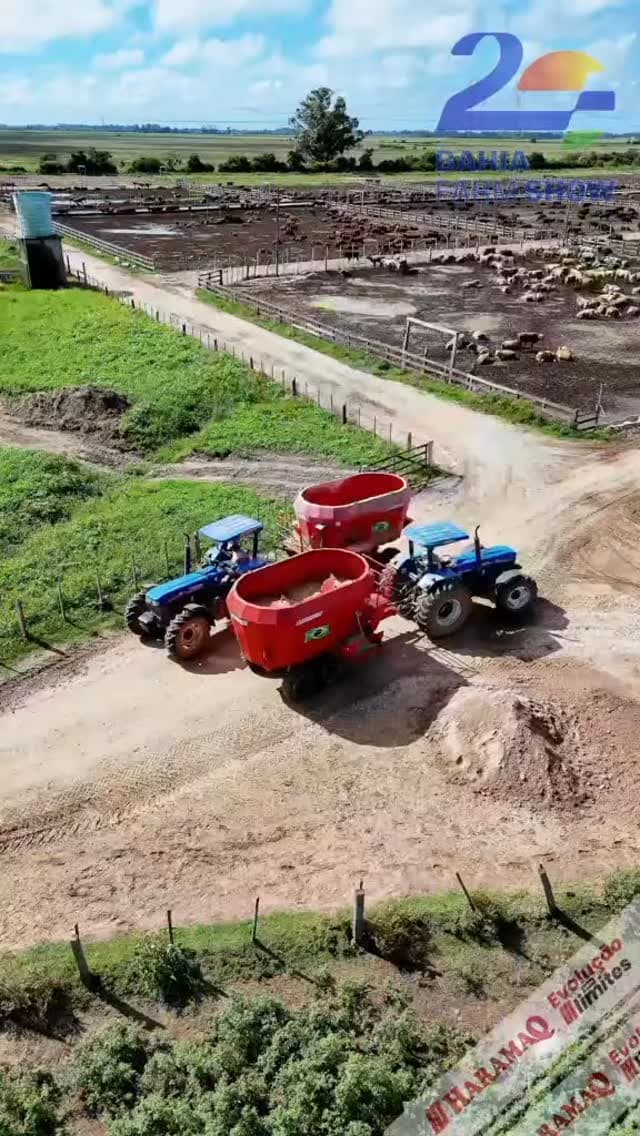 Vista aérea de propriedade rural com dois tratores puxando vagões forrageiros Haramaq vermelhos, com gado ao fundo.