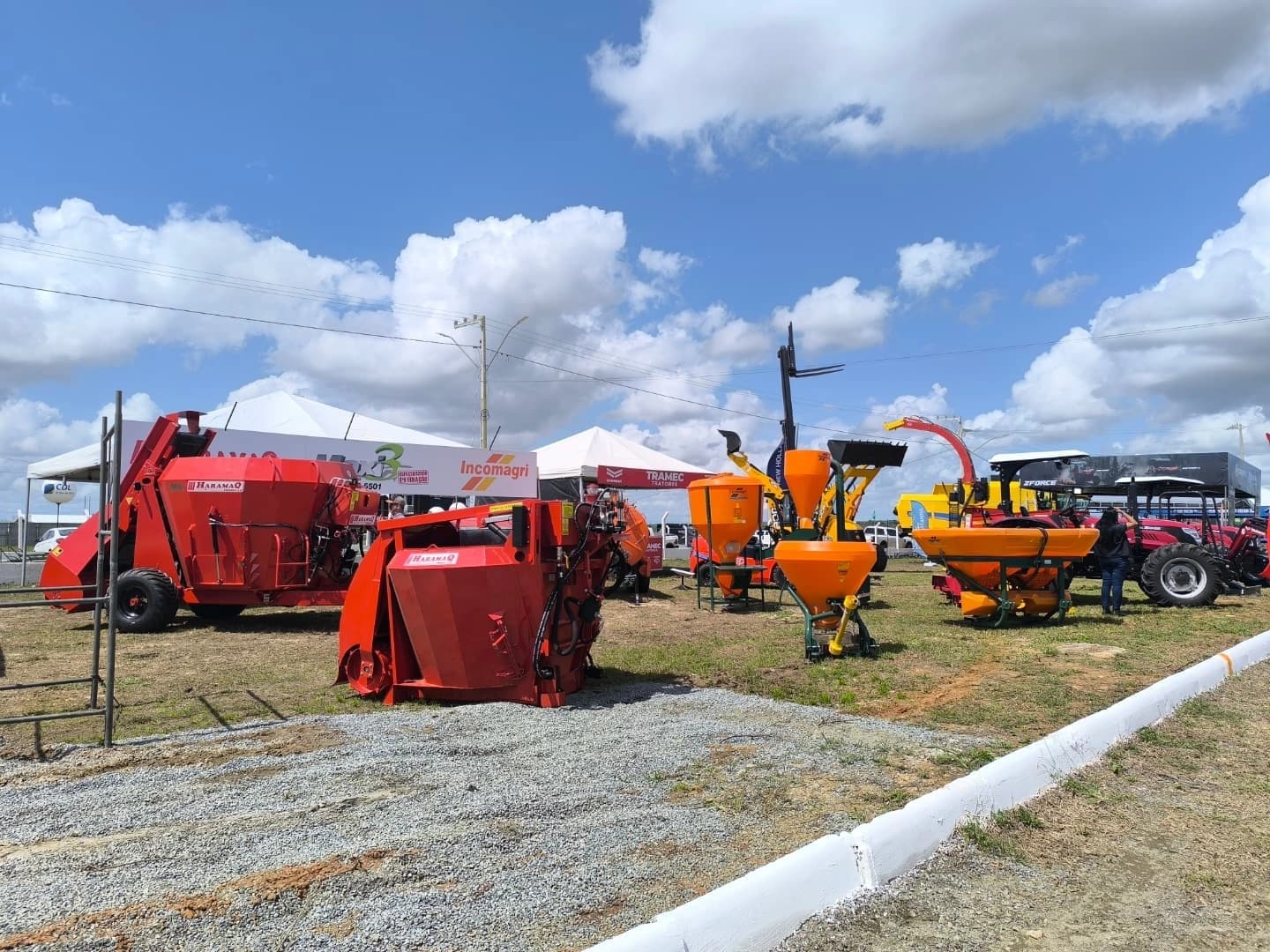 Estande da JSE em feira agrícola com misturadores Haramaq, distribuidores e tratores expostos sob céu aberto.